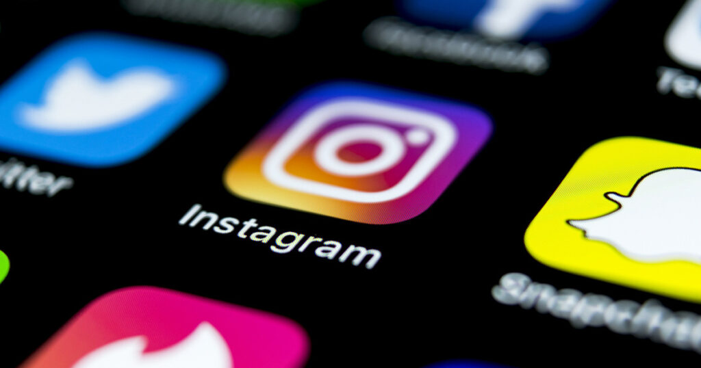 Apple iPhone X on office desk with icons of social media network instagram application on screen. Social network. Starting social media app.